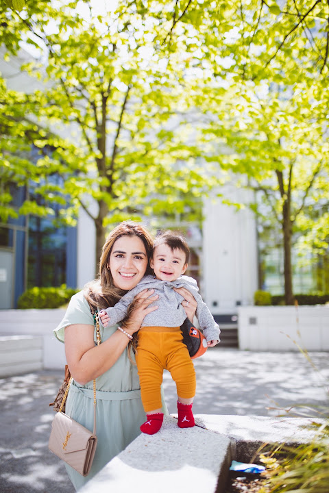 Parent holding a child beneath green trees