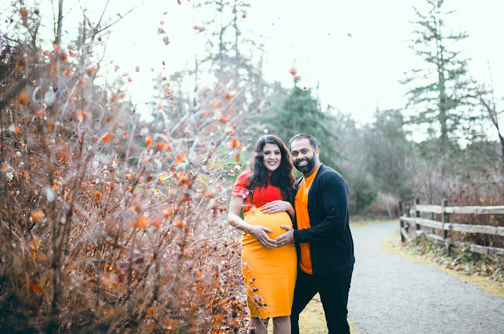 Expectant couple beside autumn foliage