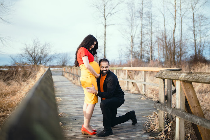 Expectant couple posing on a wooden bridge