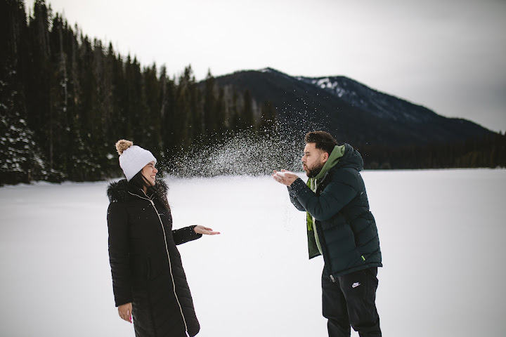 Couple playing in the snow beside a lake
