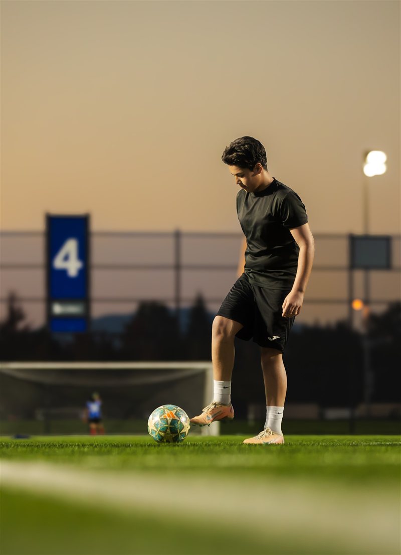 Soccer player with the ball under evening floodlights